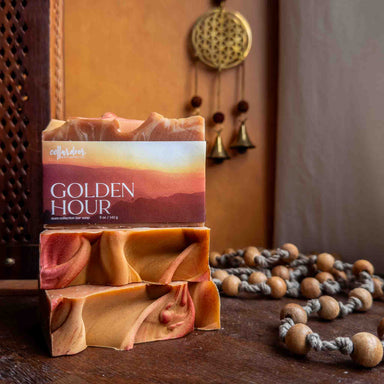 Bar of soap with packaging labeled 'Golden Hour' on a wooden surface with decorative elements.