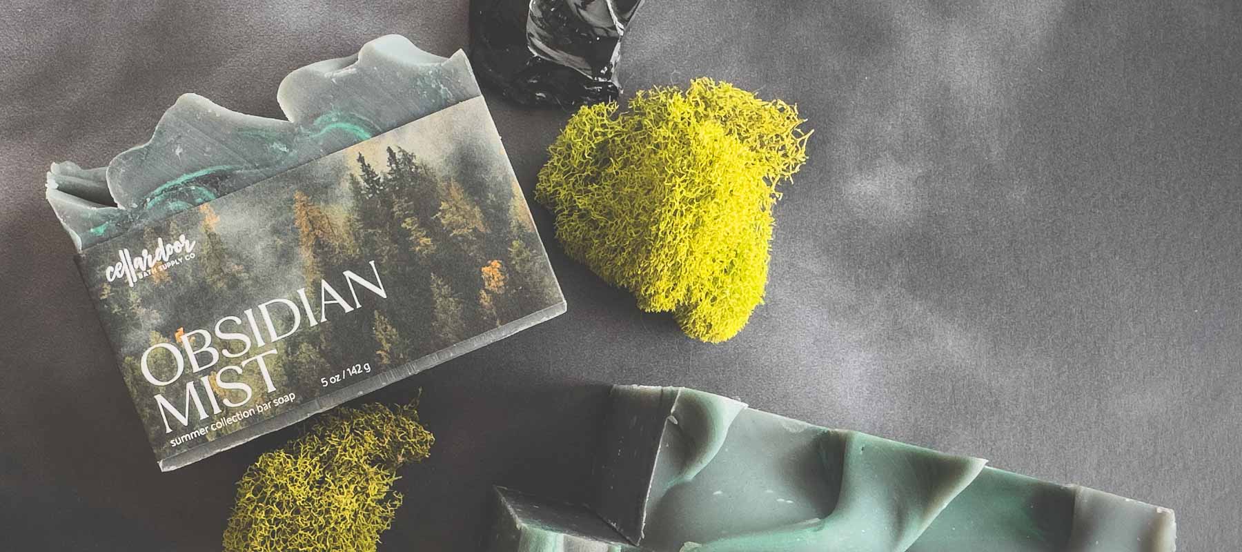 Obsidian Mist bar soap with a yellow moss-like object on a dark surface